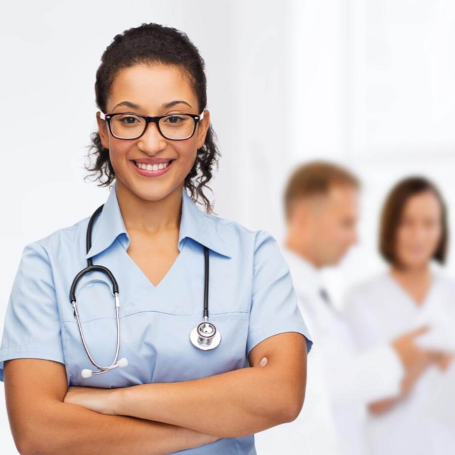 Smiling nurse with doctors in the background looking at a patient’s electronic medical record